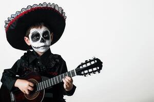 a boy playing guitar who Dressed as Mariachi Musician Entertaining with Lively Music. Day of the dead concept. photo