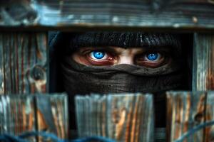 Masked Thief Peering Through Wooden Fence with Intense Blue Eyes. photo