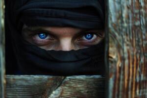 Masked Thief Peering Through Wooden Fence with Intense Blue Eyes. photo