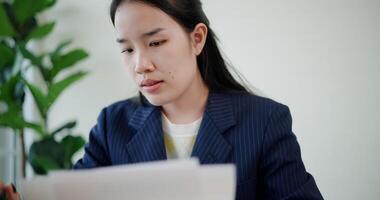 Footage dolly shot, Front view, Asian businesswoman in suit use digital tablet for work and analyze documents in small coffee shop. Work from anywhere, Remote working video