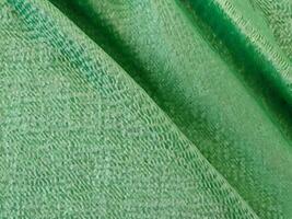 Texture, background, pattern. Texture of green silk fabric. Beautiful emerald green soft silk fabric. photo
