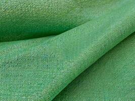 Texture, background, pattern. Texture of green silk fabric. Beautiful emerald green soft silk fabric. photo