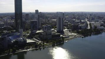 Top view of modern city with river on sunny summer day. Stock footage. High-rise buildings with modern glass buildings of modern city on river. Beautiful modern city with high-rise buildings and river photo