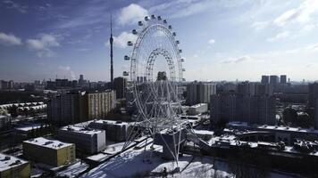 Top view of Ferris wheel in city center in winter. Creative. Large Ferris wheel stands in city on sunny winter day. Non-working Ferris wheel attraction on winter day photo