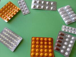 A group of pills are arranged in a circle on a green table The pills are of different colors and shapes, and they appear to be in various stages of use photo