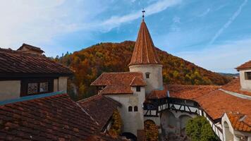 Bran, Romania, 2023 - Red tiling on the roofs of old Bran castle in Romania. Mount covered with colorful forest at backdrop. video