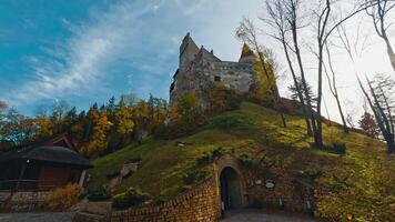 Bran, Romania, 2023 - Secret entrance to the castle standing on the high hill. Low angle view on Bran Castle in colorful autumn season. video