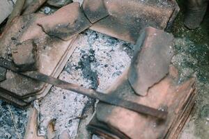 Remnants of burnt charcoal, with ash and blackened fragments, highlighting the aftermath of a fire photo