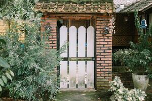 Wooden door covering a house gate, set against a backdrop of red brick and tiled roof, blending traditional charm with durability photo