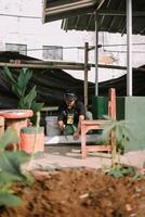 Bogor, Juni 17 2024. A man cuts wooden blocks to prepare a base for slaughtering sacrificial animals photo