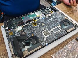 Computer technician disassembling mainboard with circuit of laptop repairing and upgrade technology photo