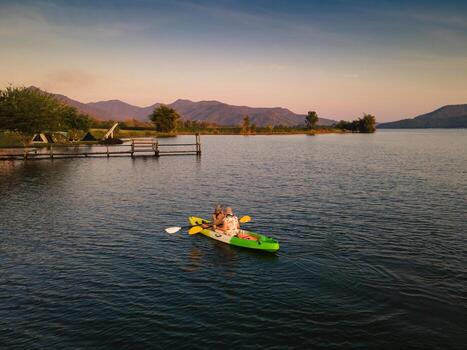 Tourist couple canoeing on the lake in countryside at evening photo
