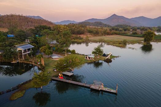 Campsite resort surrounded mountain with wooden pier on reservoir in countryside at evening photo