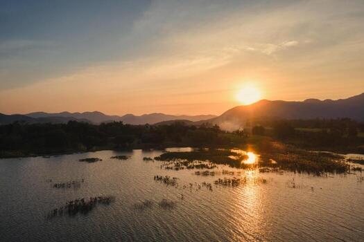 Scenery of sunset over mountain range and reservoir in countryside photo