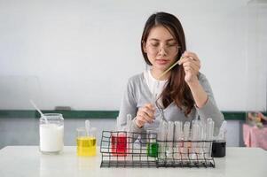 Student asian woman making analyzing and mixing liquid in test tube, color beaker at experiment laboratory in sciense class photo