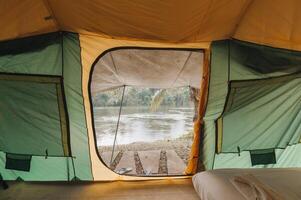 Inside of large comfortable camping tent on campground in the tropical forest by riverside on vacation photo