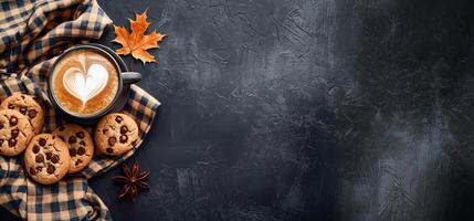 Autumn background with plaid, chocolate chip cookies and coffee cup with foam leaf on black table top view copy space banner autumn concept photo