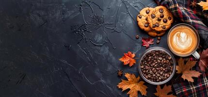 Autumn background with plaid, chocolate chip cookies and coffee cup with foam leaf on black table top view copy space banner autumn concept photo