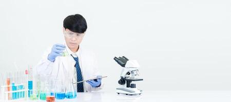 Portrait asian man student scientist wearing a doctor gown in the lab looking hand at chemist. caused by mixing reagents in scientific research laboratories with test tubes and microscope on the table photo