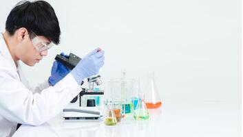 Portrait asian man student scientist wearing a doctor gown in the lab looking hand at chemist. caused by mixing reagents in scientific research laboratories with test tubes and microscope on the table photo