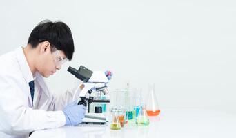 Portrait asian man student scientist wearing a doctor gown in the lab looking hand at chemist. caused by mixing reagents in scientific research laboratories with test tubes and microscope on the table photo