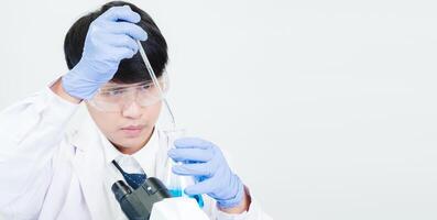 Portrait asian man student scientist wearing a doctor gown in the lab looking hand at chemist. caused by mixing reagents in scientific research laboratories with test tubes and microscope on the table photo