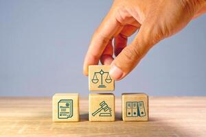 Hand holding wooden blocks with law or legal symbol on the table photo