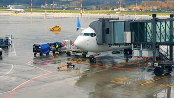 Krakow Poland 01.07.2024 Airplane at Airport Gate in Rain. An airplane docked at an airport gate on a rainy day. video