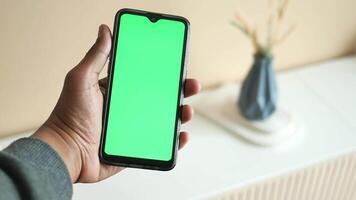 holding smart phone with green screen and home interior decoration on table video