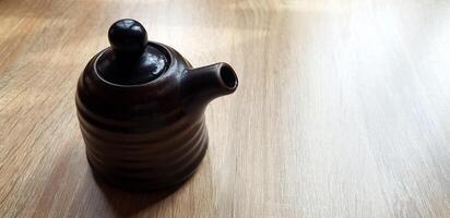 Black ceramic jug or mug tea putting on the wooden table with copy space. Sigle object, Dishware in Japan style,, Design and Container concept. photo