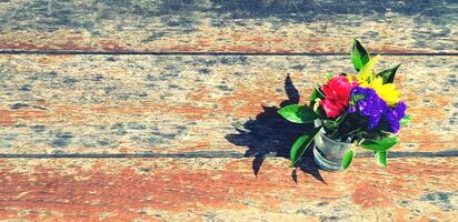Vase of colorful flower putting on grunge wooden table or background with copy space in vintage color style. Decoration, Beauty of Nature and Group of flower concept. photo