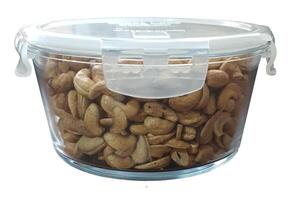 Selective focus side lit view of cashew nuts in glass jar set on cream shiny table and plain background photo