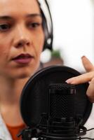 Blogger woman speaking about lifestyle in podcast using professional recording technology in home studio. Content creator making new serires for channel, streaming online broadcast on youtube photo
