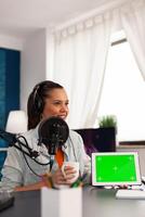 Famous blogger influencer filming of tablet with green screen in home studio podcast. Social media content creator making new serires for her channel, streaming online broadcast photo