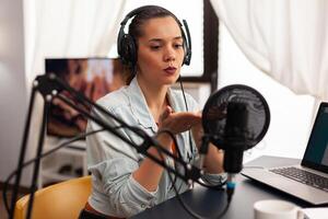Influencer content creator blowing kisses in digital marketing concepts. Blogger speaking and recording online talk show at studio using headset, professional microphone looking at camera for podcast photo