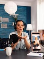 Blogger creator giving blowing kisses while recording talk show podcast. Social media influencer making professional content with modern equipment and digital web internet streaming station photo