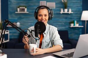 Influencer wearing headphones recording new podcast series at home studio for youtube channel. On-air online production internet broadcast show host streaming live social media content photo