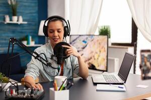 Vlogger recording blog with modern equipment in home studio podcast. New media star looking at camera for digital broadcast and having fun using technology to connect with audiences photo