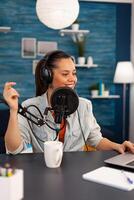 Vlogger looking at laptop while asking her audience to subscribe on her youtube channel. Digital influcencer recording talk show using modern equipment in home studio podcast photo