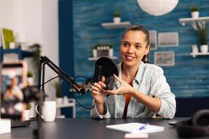 Influencer blogger smiling at camera while recording mouse review for followers. New media star on social media making with professional equipment for online internet podcast show. photo