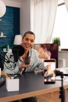 Vlogger smiling for audience and starting to review new mouse in her home studio podcast with professional equipment. Media star influencer on social media recording to connect with public. photo