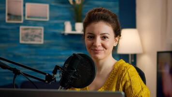 Social media influencer smiling at camera sitting in home studio ready for streaming new podcast. On-air online production internet broadcast show host streaming live content record digital blog photo