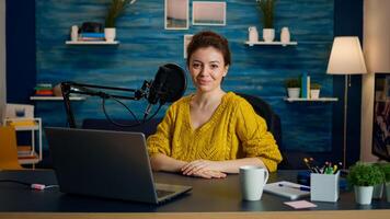 Portrait of young vlogger working in cozy studio, smiling at camera ready to start new podcast show. On-air online production internet broadcast show host streaming web content record digital blog photo
