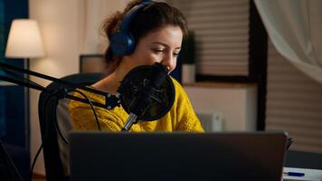 Happy blogger reading messages of fans using smartphone sitting in home podcast studio during livestreaming, recording. Online show On-air production internet broadcast host streaming live content photo