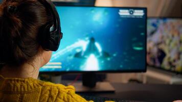 Back view of professional online gamer woman playing shooter game. Pro esport team player streamer playing gaming tournament on powerful RGB computer, using modern streaming technology photo