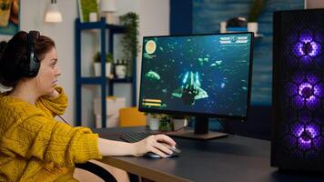 Focused woman gamer sitting on desk, putting on headset with a mic and starts playing game. Online streaming cyber performing on powerful personal computer during gaming tournament photo