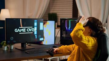 Angry woman wearing VR headset getting off after losing at online shooter game. Virtual shooter game championship in cyberspace, esport player playing with wireless controller during gaming tournament photo