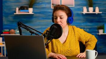 Famous blogger opening laptop and reading aloud in microphone recording podcast in modern studio creating content. On-air online production internet broadcast host streaming live show for social media photo