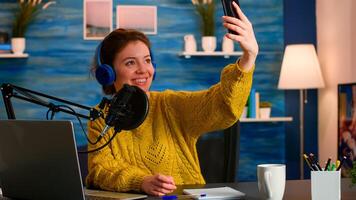 Social media influencer using phone for taking selfie recording podcast series for audience. On-air online production internet broadcast show host streaming live content for digital vlog photo