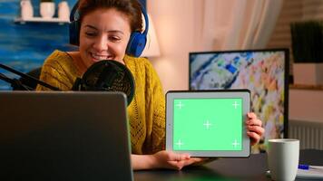 Blogger talking into microphone holding notepad with green screen during entertainment podcast. On-air production internet broadcast host streaming live content using chroma key, mockup display photo